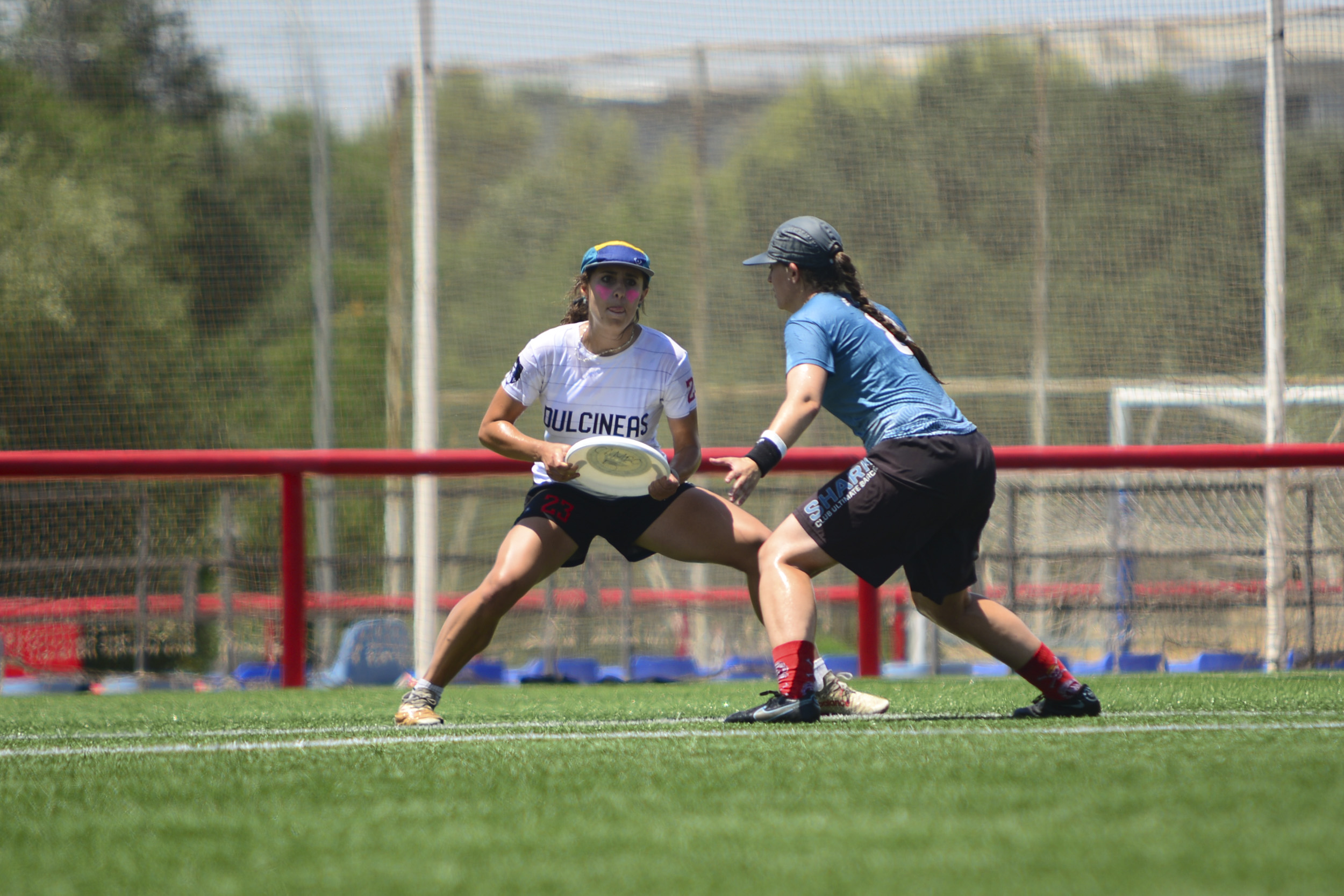 Jugadora de Dulcineas pivota con el disco mientras una defensora la marca durante un partido de Ultimate Frisbee en césped