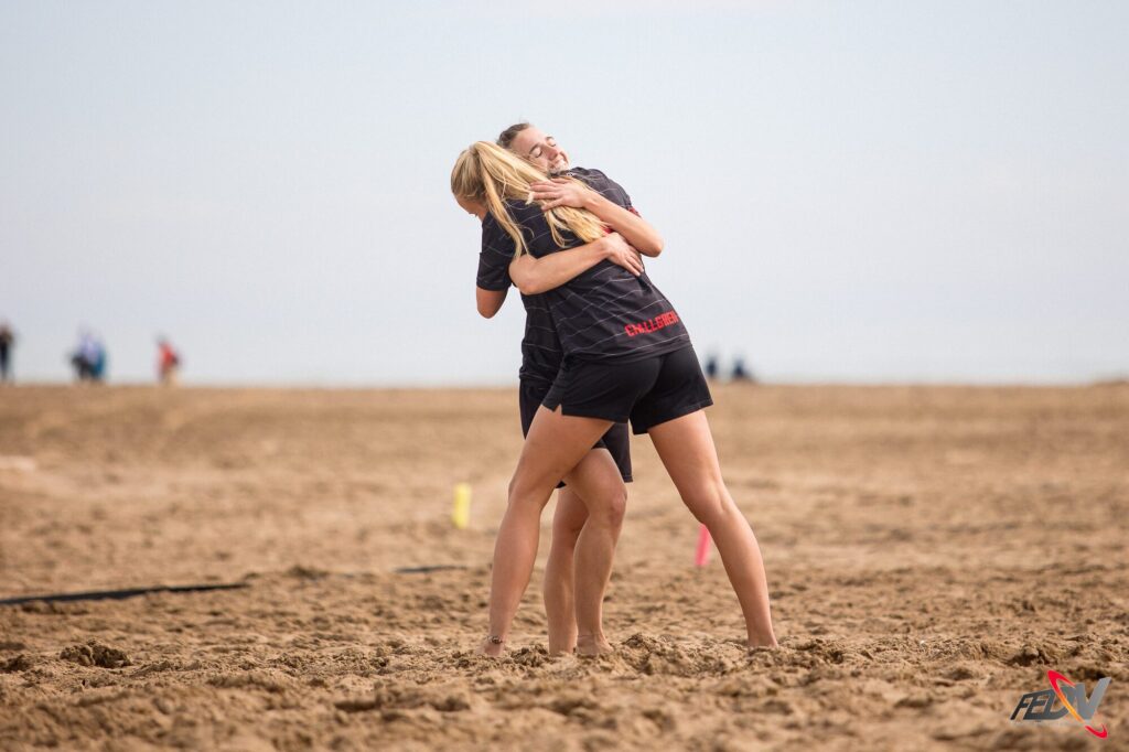 Dos jugadoras de Dulcineas se abrazan y celebran en la arena tras un partido de ultimate frisbee playa