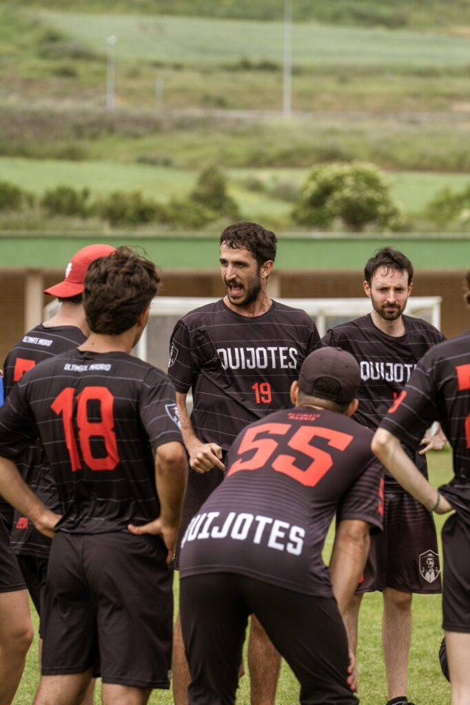 Los Quijotes forman un circulo de equipo antes de un punto en un partido de ultimate frisbee en cesped
