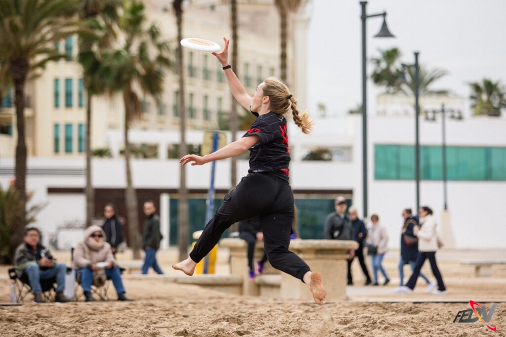 Jugadora de Dulcineas salta para atrapar el disco durante un partido de ultimate frisbee en playa