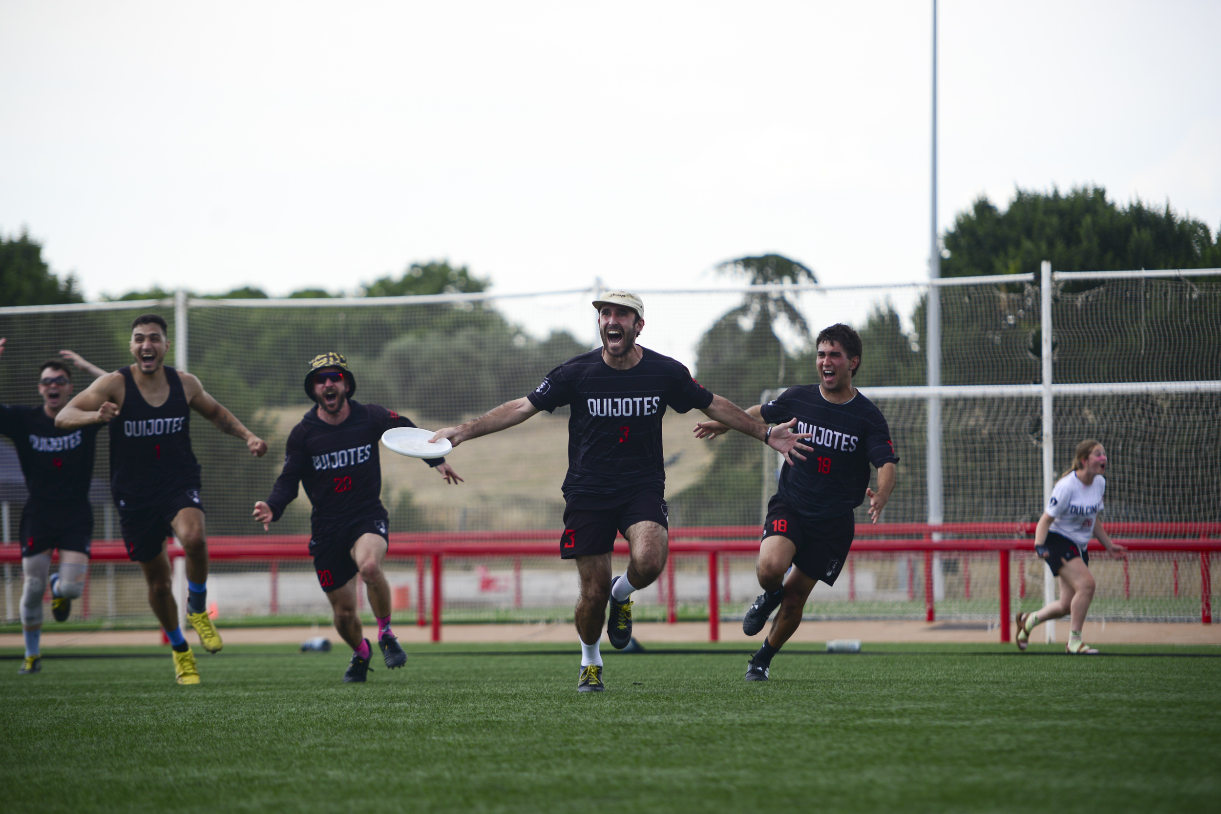 Jugadores de Quijotes corren con los brazos abiertos celebrando un punto durante un partido de Ultimate Frisbee